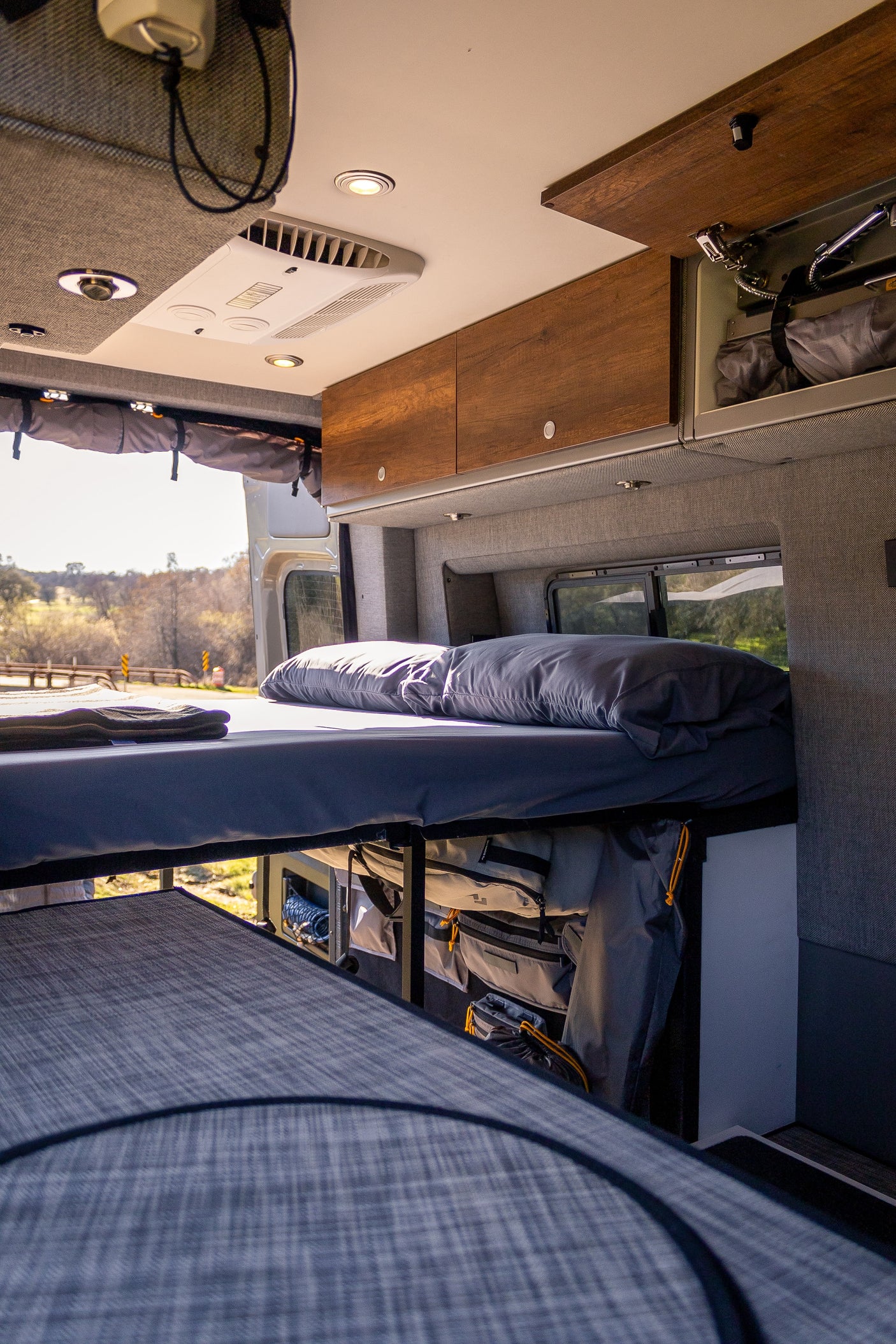 Spacious RV rental interior with bunk beds, overhead storage, and scenic views, ideal for travel and camping.