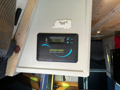 Renogy solar charge controller showing 14.3V in an RV rental, providing power status for an off-grid adventure.