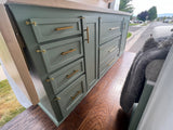 Green custom cabinets with gold hardware inside an RV rental, showcasing practical storage and wood floors.