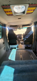 Spacious RV rental interior showcasing front seats, dashboard, overhead fan, and a versatile floor plan with tracks.
