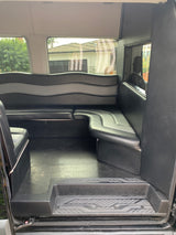 Spacious RV rental interior with black and grey lounge seating, seen through side door.