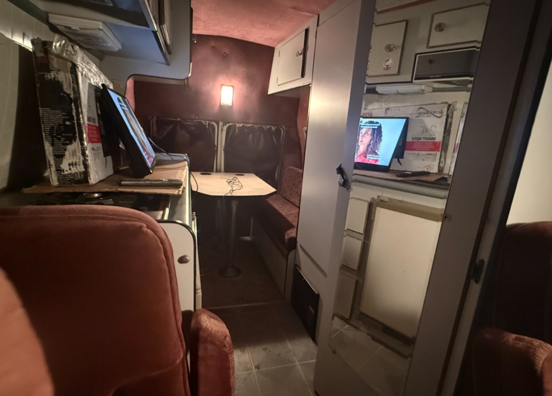  parked on a sunny urban street in California (8YGD709).|Cozy RV rental interior: plush reddish-brown seats — photo 5