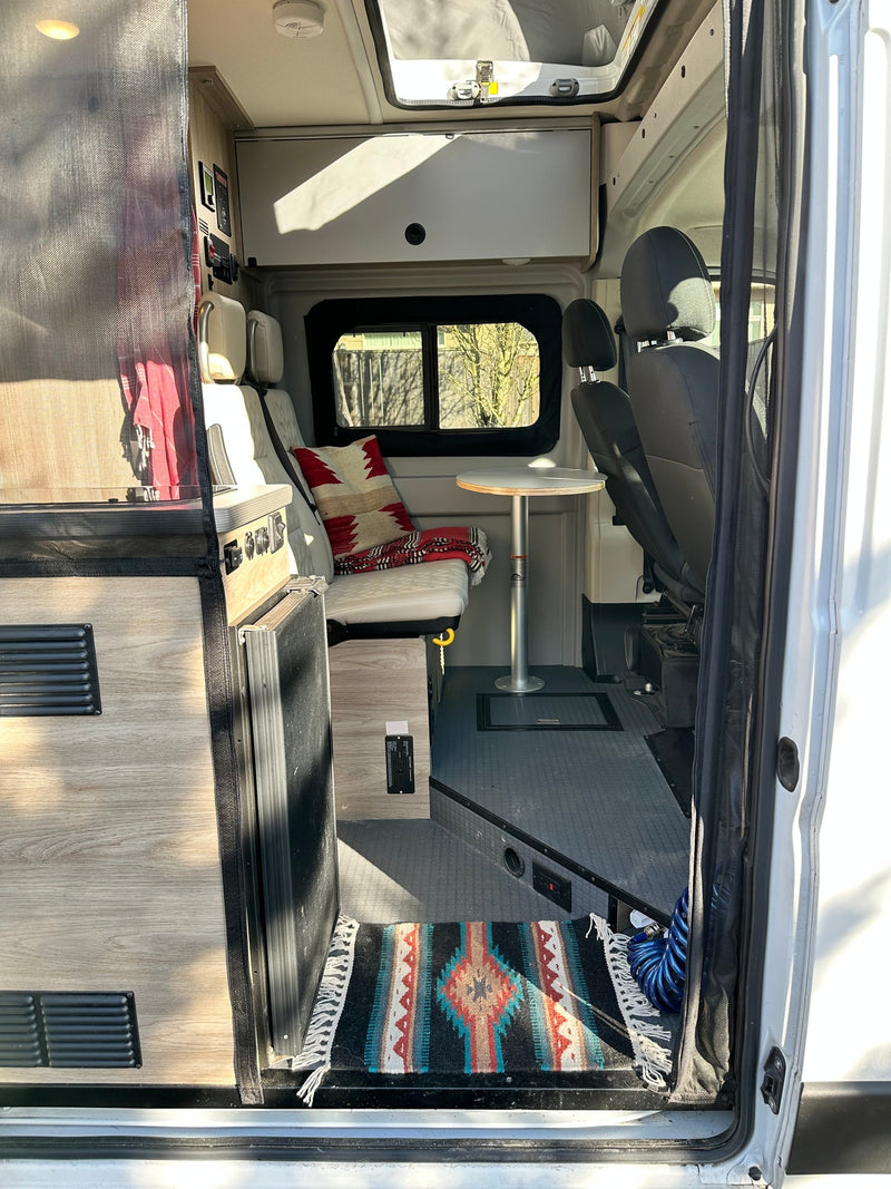 Explore this inviting camper van RV rental, featuring a kitchenette, bench seating, table, and front seats. — photo 7
