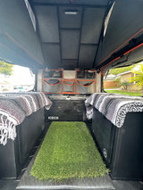 RV rental overland interior: modular storage, ICECO fridge, comfy blankets, & an artificial grass mat.