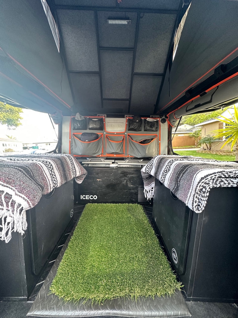 RV rental overland interior: modular storage, ICECO fridge, comfy blankets, & an artificial grass mat. — photo 14