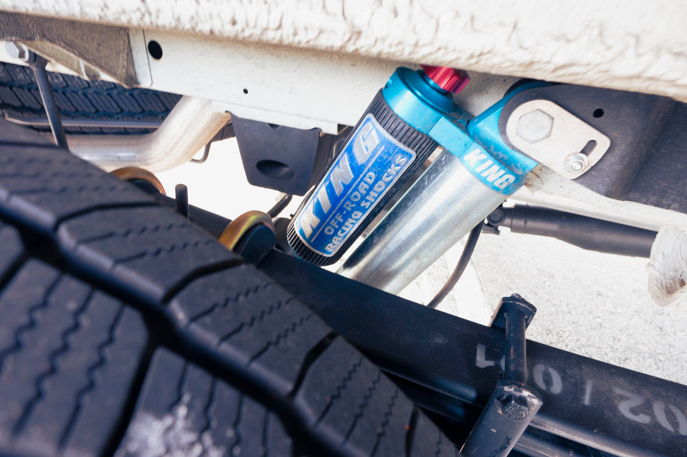 Blue King Off-Road Racing Shocks and heavy-duty tire seen from below an RV rental. Enhanced suspension for any adventure.