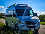 Silver Mercedes-Benz Sprinter camper van, ideal for rv rental, parked outdoors under a bright blue Montana sky.