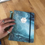 Blue marbled planner, 'Make it Happen' label, and diamond pen. Ready for your next RV rental adventure plans!