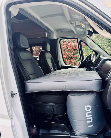 Cozy RV rental setup: Luno inflatable mattress spans the front seats, creating a convenient sleeping area in this camper van.