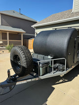 A rugged black off-road teardrop trailer with a front-mounted spare tire, perfect for RV rental adventures.