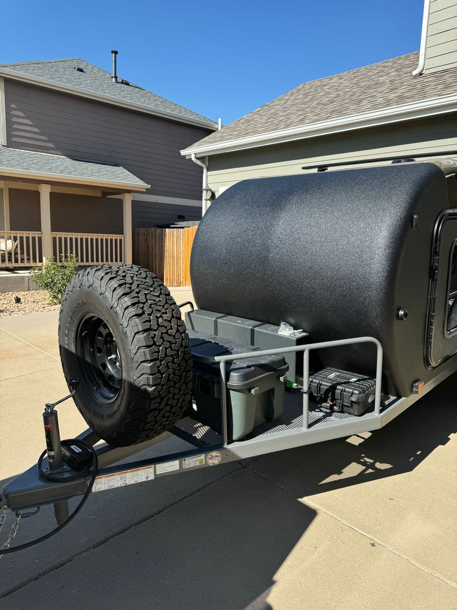  ready for adventure.|A rugged black off-road teardrop trailer with a front-mounted spare tire