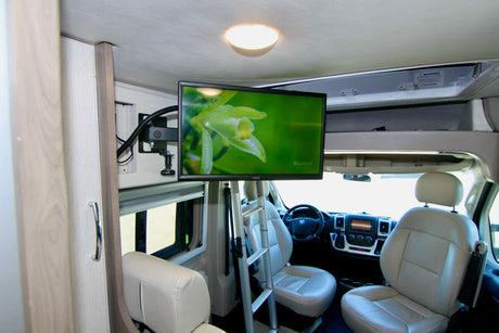 Inside an RV rental: a modern interior with a mounted TV, comfortable front seats, and a clear view of the cockpit.