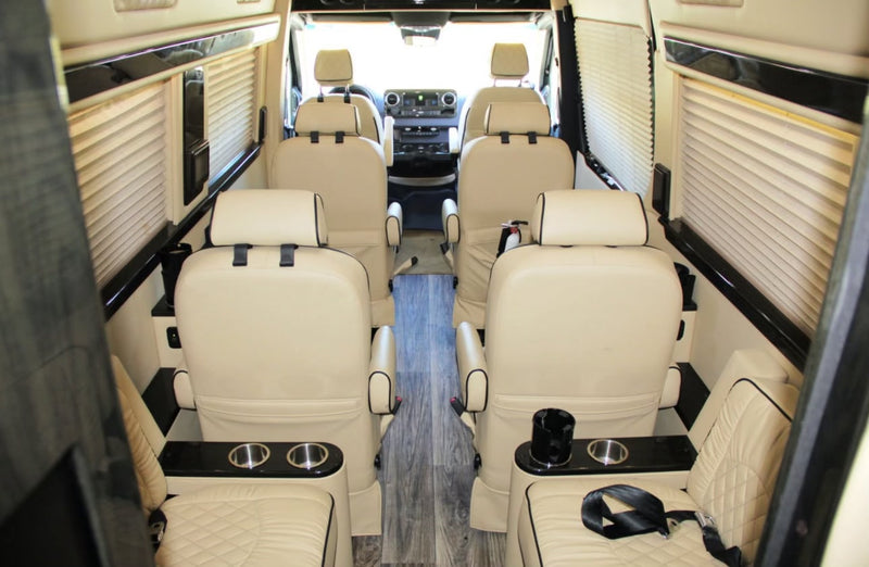 Spacious luxury RV rental interior: beige captain's chairs, wood floor, ideal for comfortable group travel. — photo 8