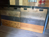 Custom multi-toned wood paneling & storage with black handles inside an RV rental, featuring a grey laminate floor.