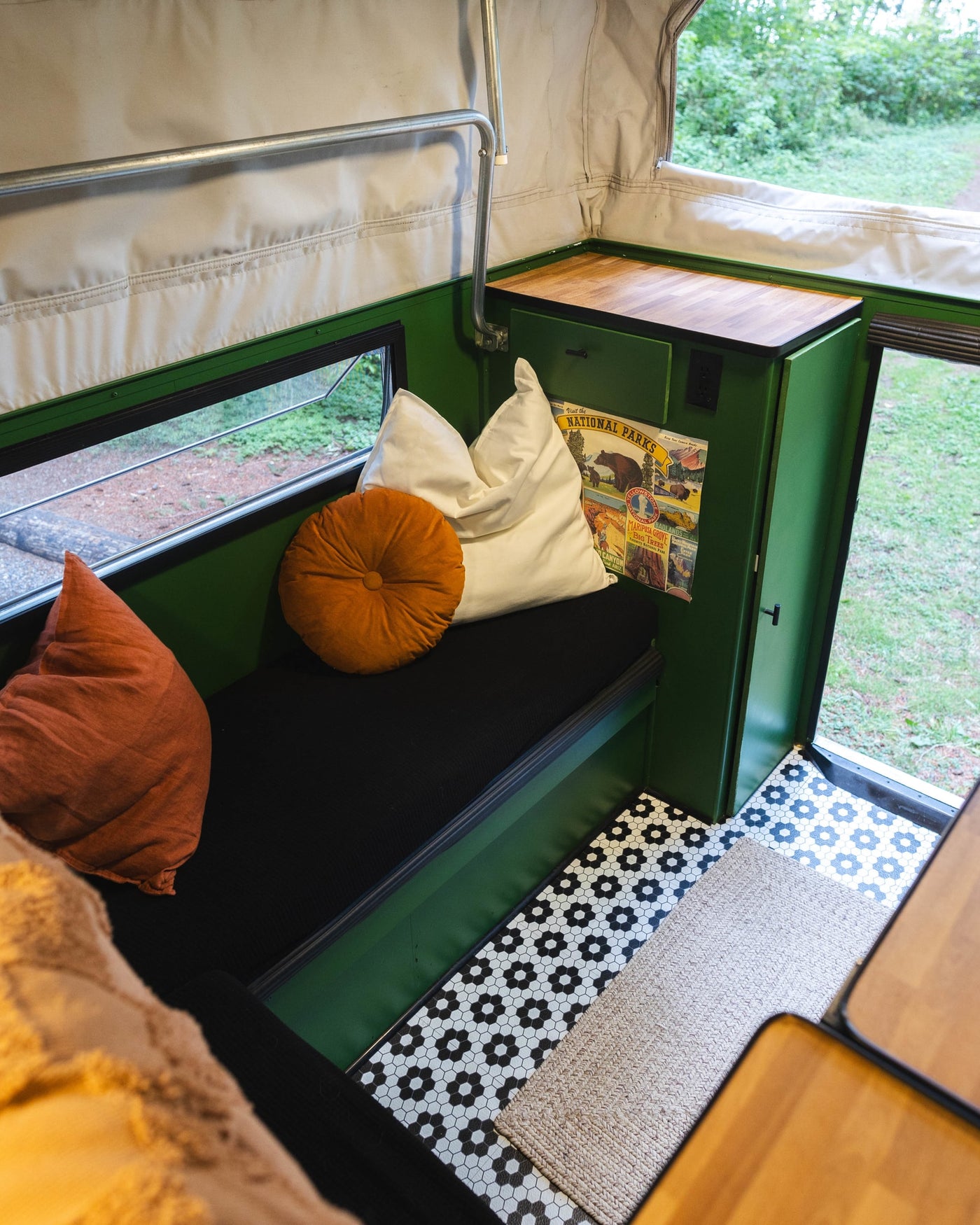 Cozy RV rental interior featuring green walls, National Parks decor, comfy cushions, and unique hexagonal tile flooring. — photo 9
