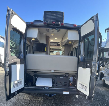 Explore this RV rental: a camper van with rear doors open, revealing a comfy bed, mounted TV, and smart storage for your adventures.