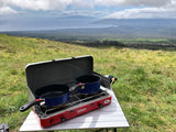 RV rental trip: Outdoor cooking on a portable stove with stunning views of the ocean and distant hills from a grassy peak.