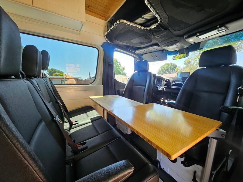Spacious RV rental interior with comfy seating and a wooden table, perfect for travel & mobile work. — photo 8