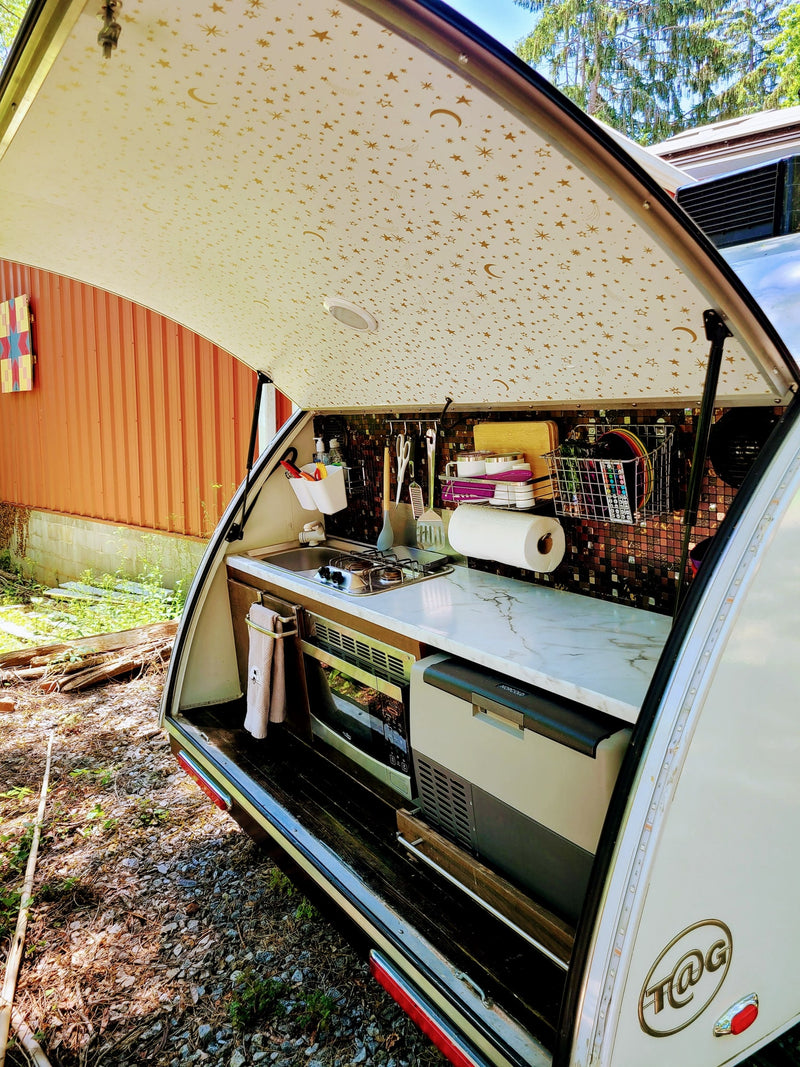  and window view of nature.|Inside a cozy RV rental: a bed with blue and purple covers — photo 5