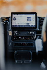 An RV rental's modern dashboard features a large infotainment screen showing music, plus climate and vehicle controls.