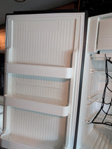 A compact rv rental refrigerator with an open door, showcasing door shelves and main compartment with a cargo net.