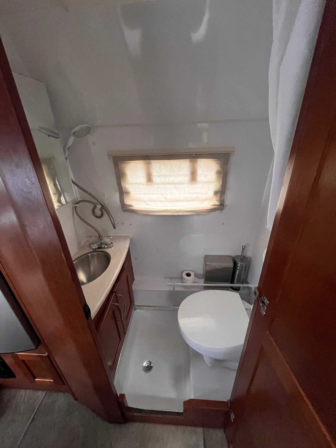 Compact RV rental bathroom with a wet bath design, featuring a sink, toilet, and integrated shower for easy travel.