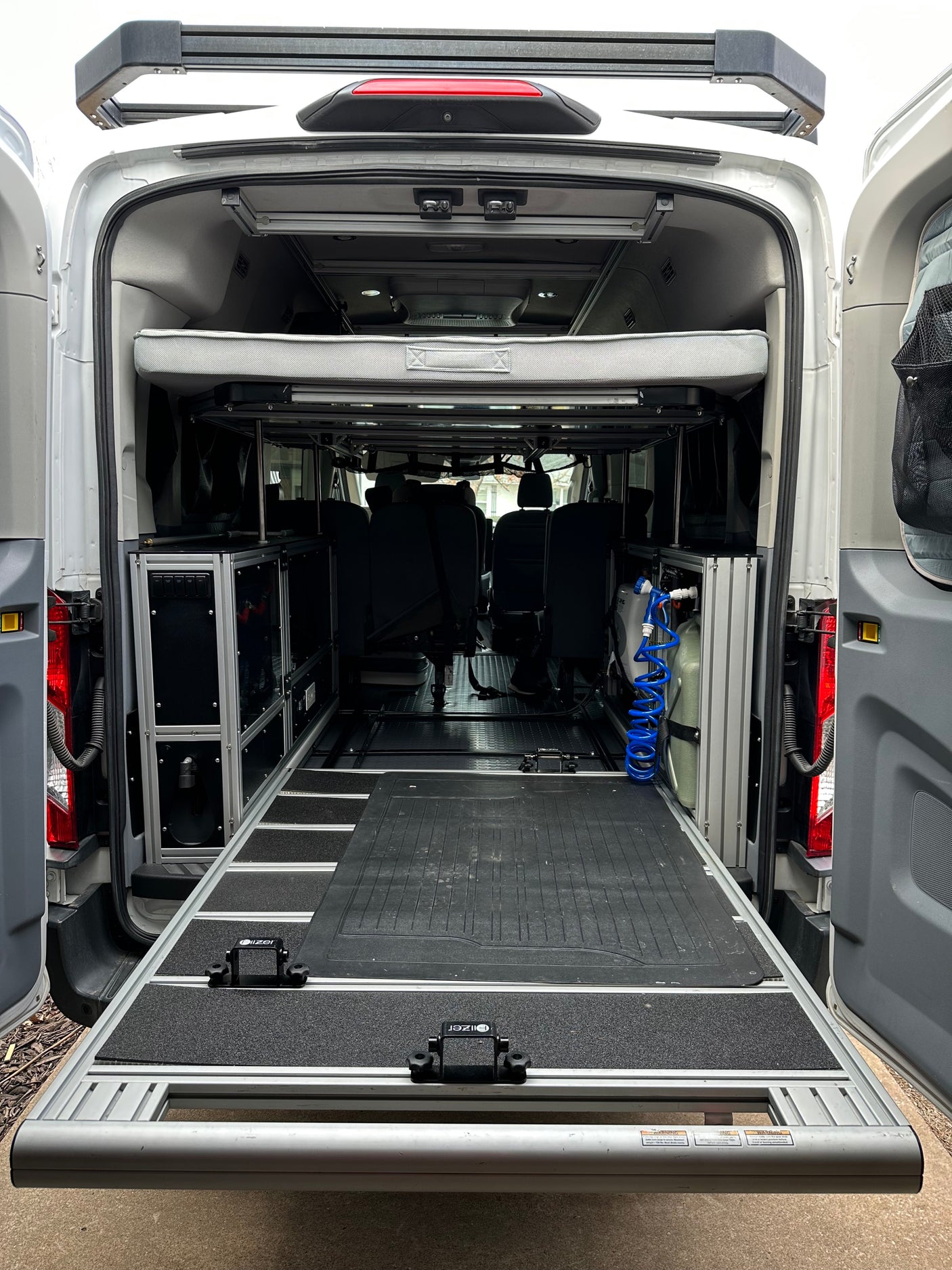 Adventure-ready RV rental: Van interior showing a pull-out bed, modular storage, and a practical rear slide-out for gear.