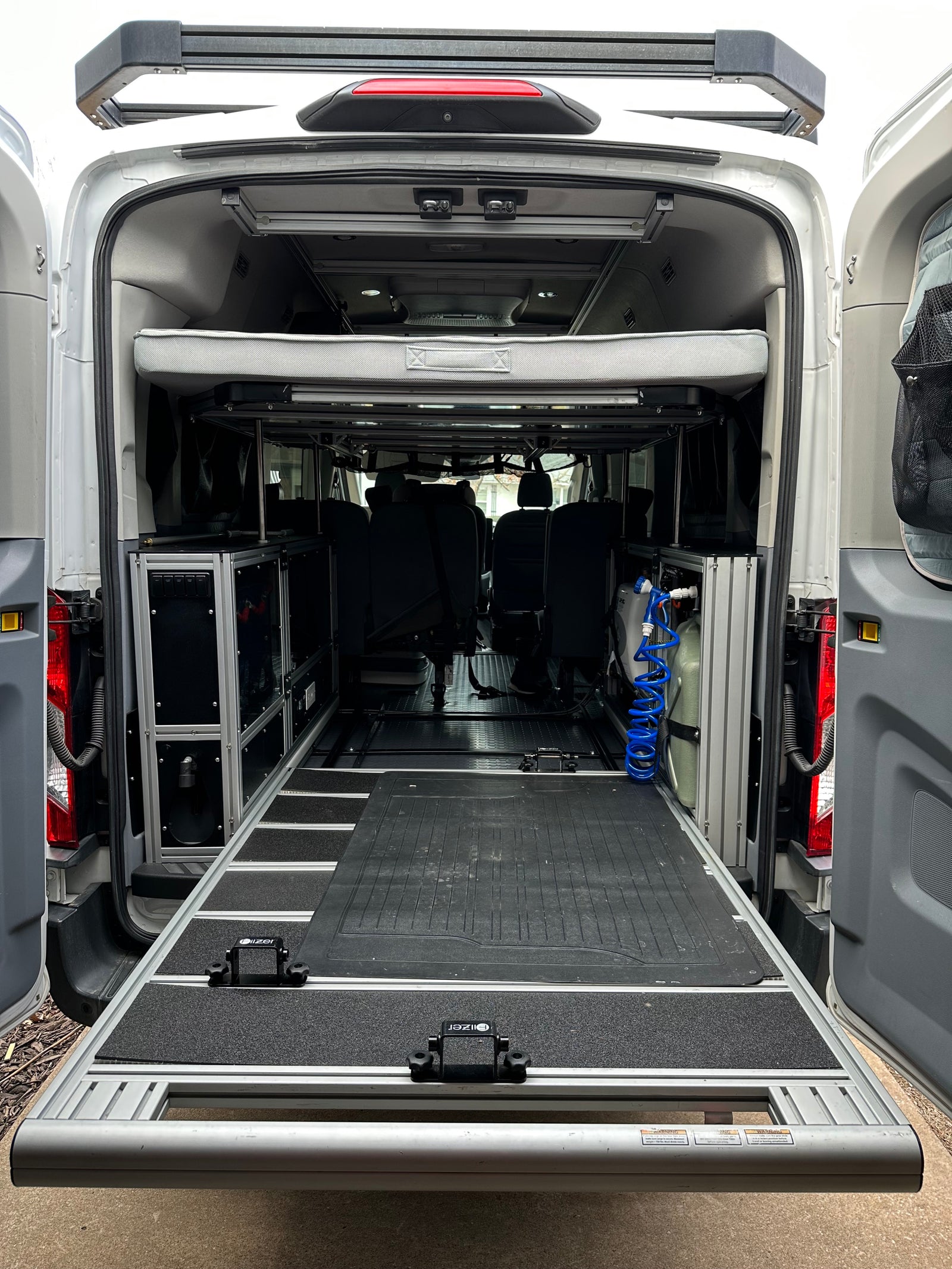 Adventure-ready RV rental: Van interior showing a pull-out bed, modular storage, and a practical rear slide-out for gear.