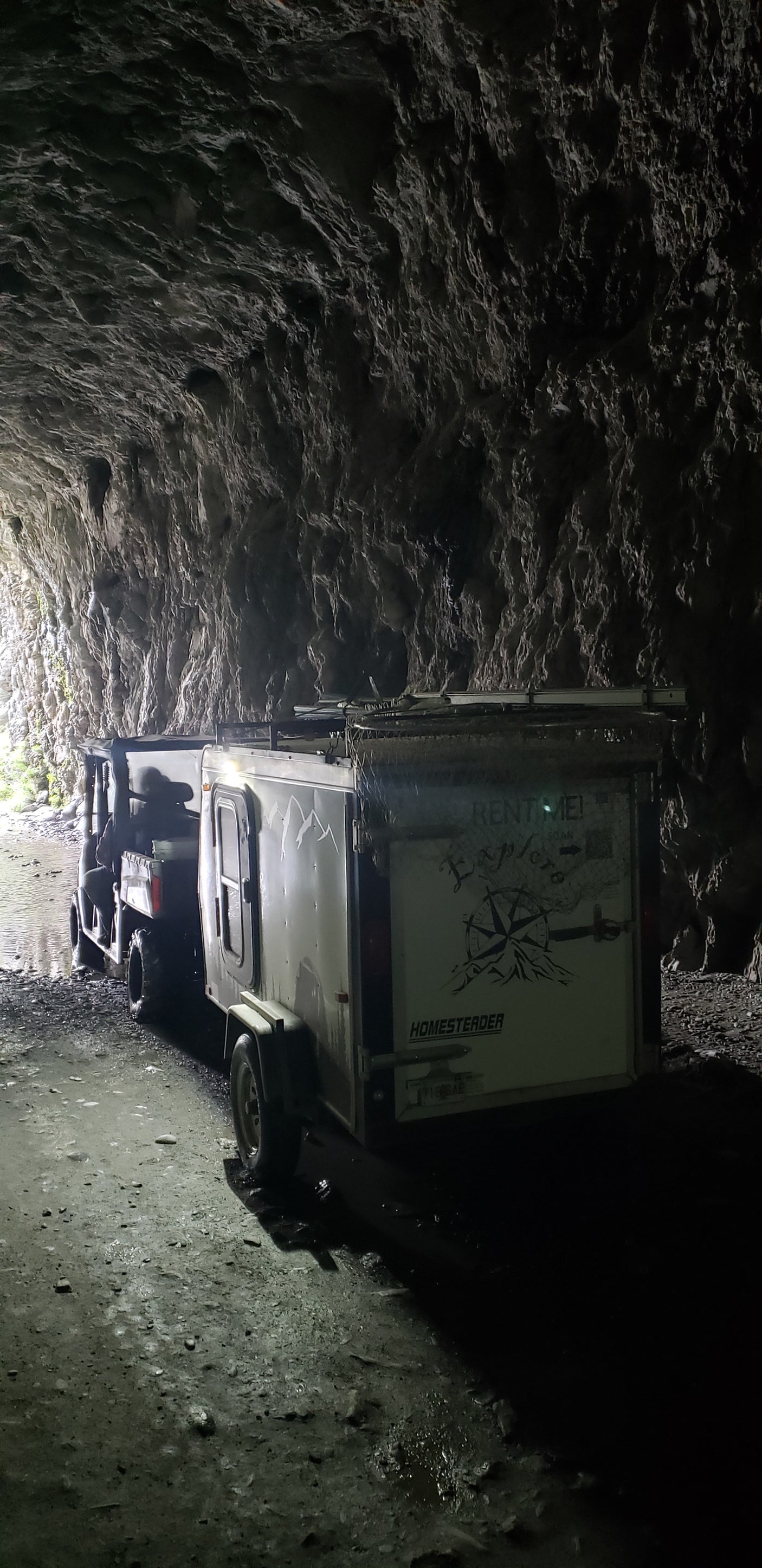 An off-road RV rental vehicle and trailer navigate a dark, wet cave. Perfect for adventure exploration!