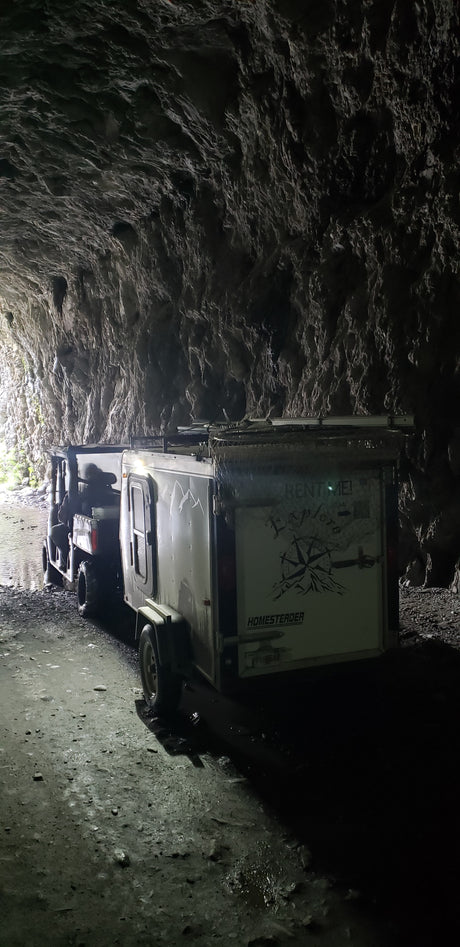 An off-road RV rental vehicle and trailer navigate a dark, wet cave. Perfect for adventure exploration!