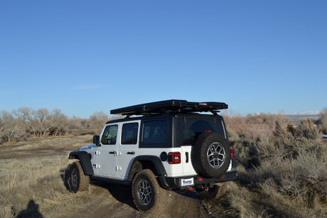 Explore trails with this white Jeep Wrangler Rubicon, featuring a rooftop tent. Great rv rental for off-road adventures.