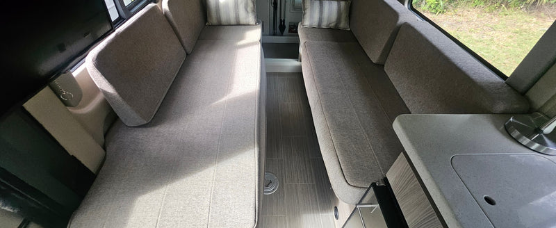  parked on grass under a cloudy sky.|Interior view of an RV rental with long — photo 6
