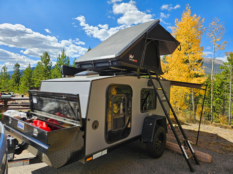 Teardrop camper trailer with a NaturNest rooftop tent, parked in a scenic fall mountain setting, great for an RV rental.
