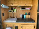RV rental kitchenette: sink, paper towels, spices, dishes, and knife set ready for your travels.