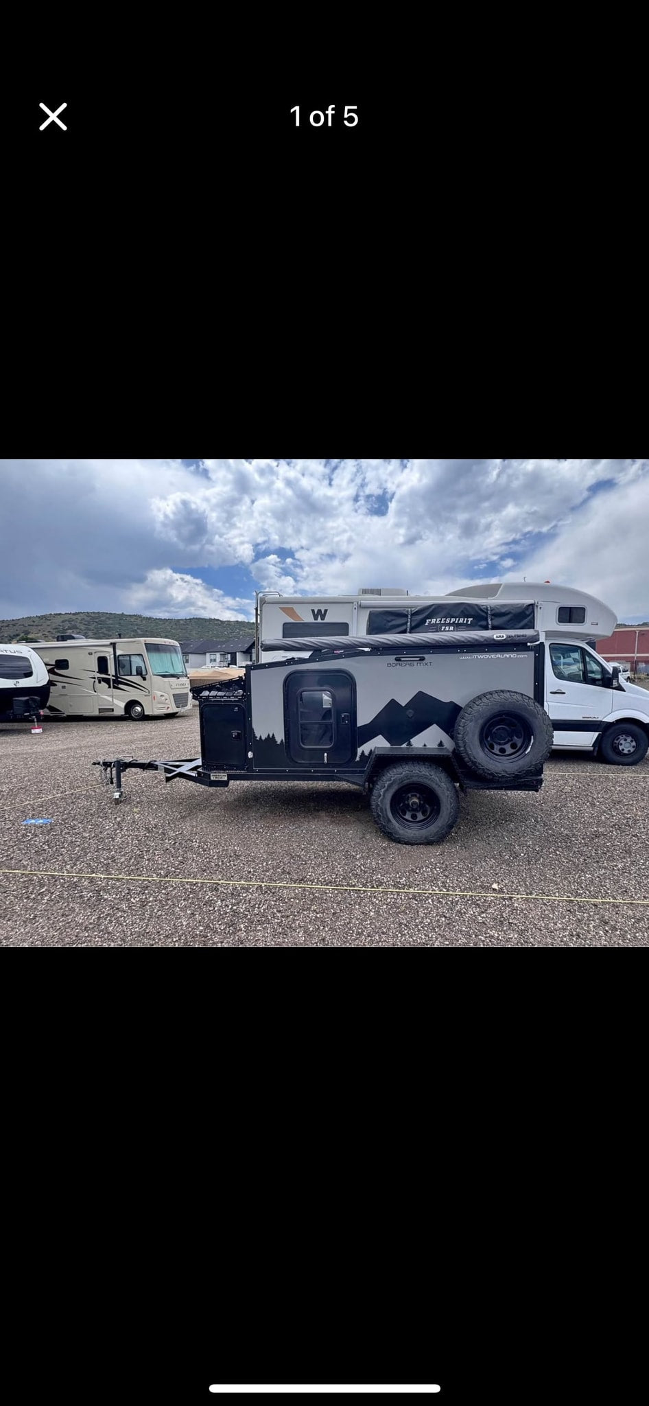 Rugged Boreas MXT off-road camper trailer with mountain graphics and spare tires, parked on gravel alongside other rv rental options. — photo 4