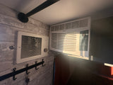 Inside an RV rental: a Haier AC unit and a Broan vent on a brick-patterned wall, with keys on a coat rack below.