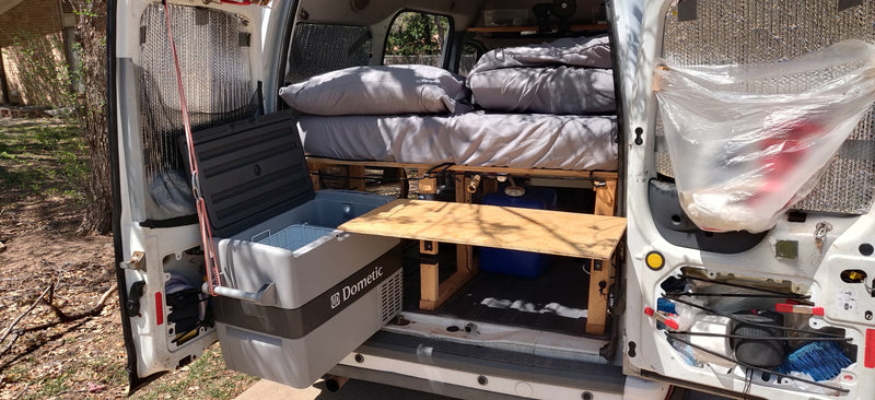 RV rental: Camper van interior with bed, Dometic cooler, and water system. Compact setup for comfortable travel. — photo 13