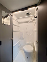 Explore this Winnebago rv rental's compact wet bath with shower, toilet, mirror, and bright LED lighting.