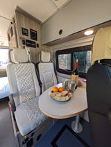 Winnebago rv rental dining area features charcuterie, wine, comfortable seating, and control panel.