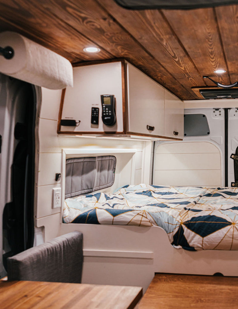  beside a cozy bed with patterned bedding in a modern rv rental.|Relax in this RV rental's cozy interior: wood-paneled ceiling — photo 9