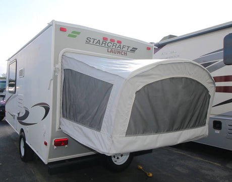 A light gray Starcraft Launch hybrid travel trailer, ready for rv rental. Its rear shows a white canvas pop-out tent with a screen.