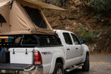 White Toyota Tacoma pickup with a rooftop tent, ready for camping. An ideal RV rental alternative for outdoor adventures.