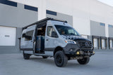 This gray Mercedes Sprinter custom adventure van rv rental, equipped for off-road, features knobby tires and an open side door.