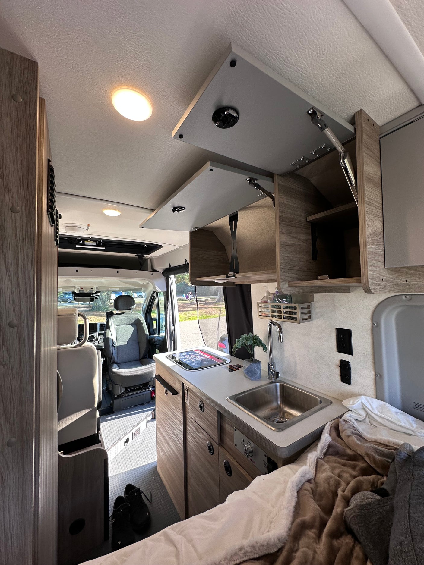 RV rental interior featuring a compact kitchenette, cozy bed, and front cabin view for comfortable travel.