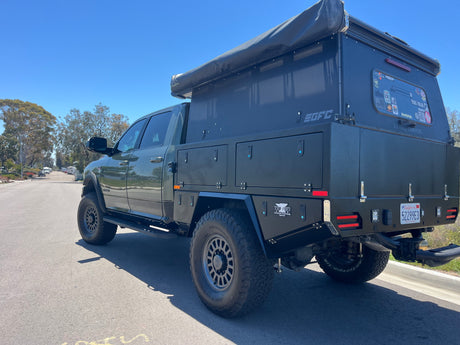 Explore with this dark green Ram truck camper, an RV rental by FORA Adventure Rentals, featuring a GFC and Tin Bin flatbed.