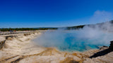 Explore Yellowstone's steaming blue thermal pool and boardwalk with an RV rental. Tourists enjoy the unique natural beauty.