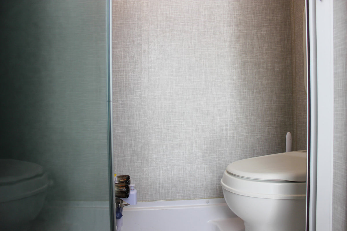 RV rental bathroom features a white toilet, textured walls, and a view through a translucent shower partition. — photo 19