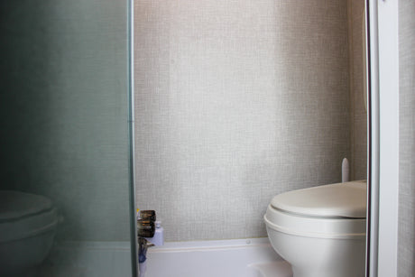 RV rental bathroom features a white toilet, textured walls, and a view through a translucent shower partition.