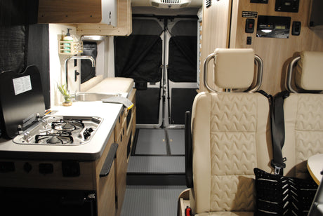 This RV rental features a compact interior with a kitchenette (sink & stove), rear passenger seating, and a Xantrex solar charge controller.