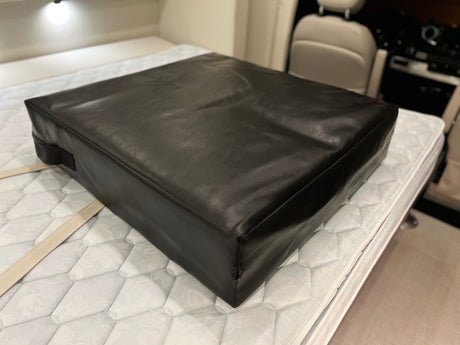 A dark leather-like cushion rests on a white quilted mattress in an RV rental interior, with a light in the background.